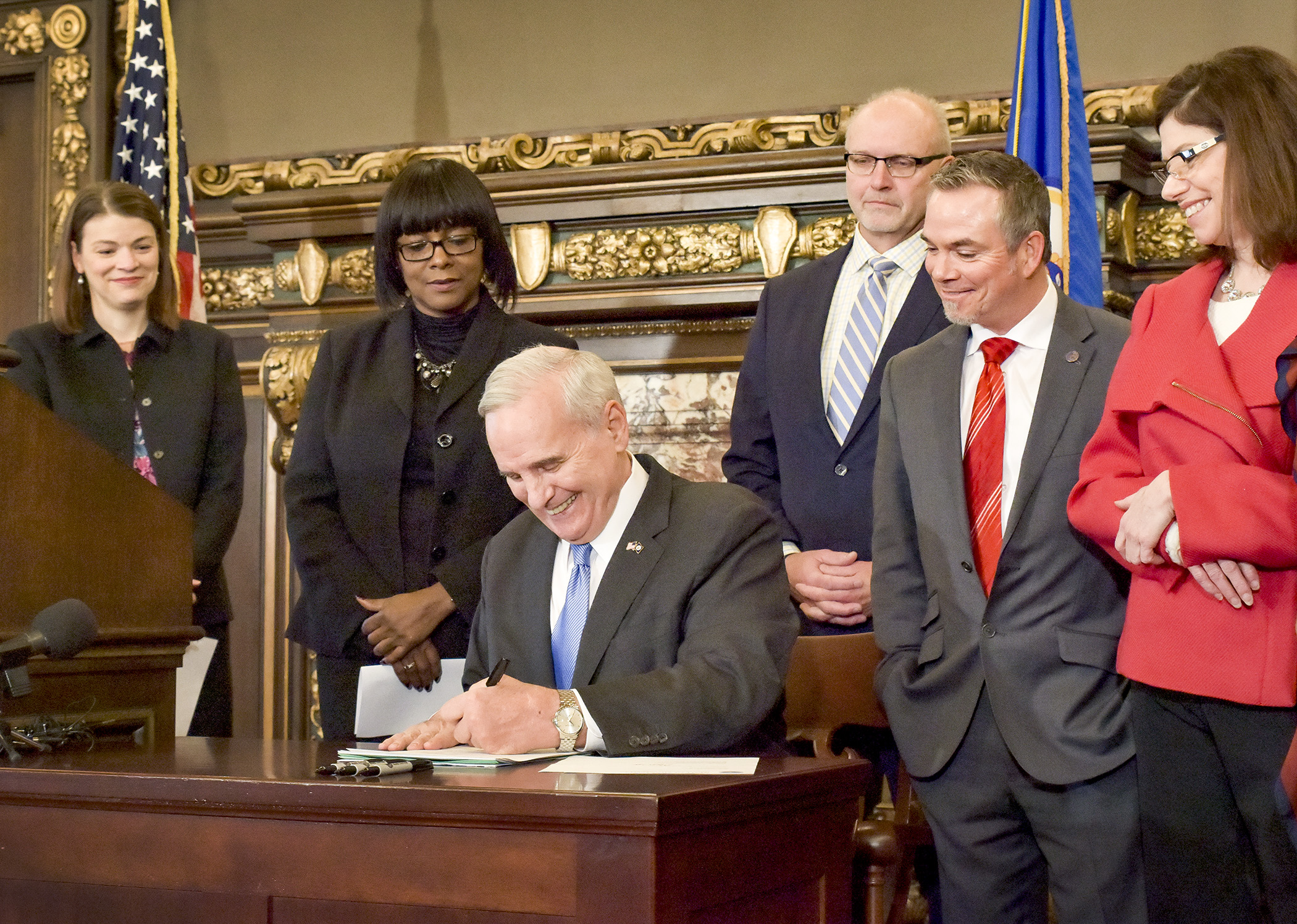 Flanked by legislators from both parties, Gov. Mark Dayton signs the tax conformity bill, HF2, into law Jan. 13. Photo by Andrew VonBank